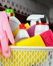 Various detergents, cleaners products, kitchen sponges and rubber gloves in the basket at the kitchen. Cleaning service concept.