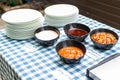 Various dip sauces on black bowls with white plates on dinner table setting Royalty Free Stock Photo