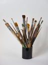 Various dirty paint brushes in a black cup isolated on white