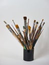 Various dirty paint brushes in a black cup isolated on white