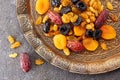 Various dried fruits on toreutic plate over stone background