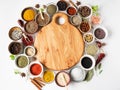 Various dry spices frame flat lay in small bowls and wood cutting board in the center on white wood background. Top view, copy