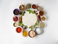 Various dry spices and raw herbs frame flat lay in small bowls and wood cutting marble board in the center on white background. Royalty Free Stock Photo