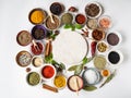 Various dry spices and raw herbs frame flat lay in small bowls and wood cutting marble board in the center on white background. Royalty Free Stock Photo