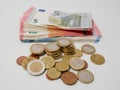 Various Euro coins and banknotes on a white desk. Notes and coins of various denominations.