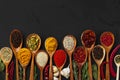 Various exotic spices in wooden spoons on dark background