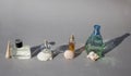 Various female and male perfume bottles with interesting shells on gray background with hard shadows standing in row