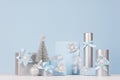 Various festive christmas gift boxes and decoration in soft light pastel blue color with shiny silver ribbons and silk bows.