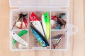 Various fishing lures in plastic box on wooden background, horizontal, top view Royalty Free Stock Photo