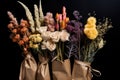 Various flowers in bunches, herbs and dried flowers in craft packaging isolated on black background