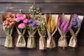 Various flowers in bunches, herbs and dried flowers in craft packaging on wooden rustic background, flatlay