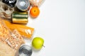 Various foods sealed in plastic bags, cans and fruits on white background, top view.