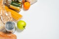 Various foods sealed in plastic bags, cans and fruits on white background, top view.