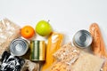 Various foods sealed in plastic bags, cans and fruits on white background, top view.