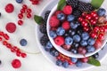 Various fresh berries close-up including blueberries, raspberries, blackberries and currants in a white cup on a white wooden back Royalty Free Stock Photo