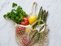 Various fresh food - vegetables and fruits in eco-friendly bag on white marble background. Vegetarian meal from the market in