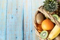 Various fresh and organic fruits in a vintage wicker basket isolated on a blue wooden table Royalty Free Stock Photo