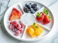 various frozen fruits in five compartment plate on white marble table. served with elegance