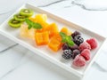 various frozen fruits in rectangular plate on white marble table. served with elegance