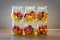 Various glasses containing vitamins with cut pieces of fruit on a wooden plate