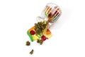 Various gummies and dried medical marijuana buds fell out of the embossed glass jar. On a white background.