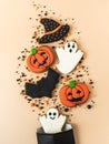 Various Halloween gingerbread cookies - Jack O`Lanterns, black hat, ghosts, bat and sugar sprinkles scattering of paper bag