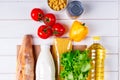 Various healthy food, tomato, bread, pasta, pepper, oil and vegetables in paper bag on white wooden background. Food