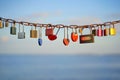 Various and heart colorful shaped love padlocks on a chain on a beautiful blue sky and sea background. Diverse locks as