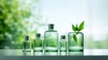 Small and large glass bottles with a green plant on a white table with a blurred forest background. Royalty Free Stock Photo