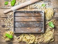 Various homemade uncooked Italian pasta and wooden tray in center Royalty Free Stock Photo