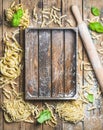 Various homemade uncooked Italian pasta and wooden tray in center Royalty Free Stock Photo