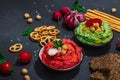 Various hummus dips, fresh vegetables and herbs. Crispy bread snacks, modern vegan healthy food