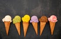 Various of ice cream flavor in cones blueberry ,green tea ,pistachio ,almond ,orange and cherry setup on dark stone background . Royalty Free Stock Photo