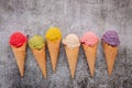 Various of ice cream flavor in cones blueberry ,green tea ,pistachio ,almond ,orange and cherry setup on dark stone background . Royalty Free Stock Photo