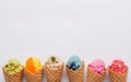 Various of ice cream flavor in cones blueberry ,strawberry ,pistachio ,almond ,orange and cherry setup on white wooden background