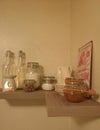 Various jars and bottles of honey nuts and sugar standing on top of a shelf