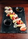 Various kinds of cheese cuts Blue cheese, Brie Cheese, Cheddar cheese served with honey and some fruits such as strawberry.
