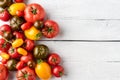 Various kinds of tomatoes on white wooden table with copyspace. Food background.