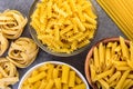 Various kinds of uncooked pasta on gray background.