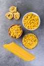 Various kinds of uncooked pasta on gray background.