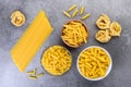 Various kinds of uncooked pasta on gray background.