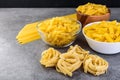 Various kinds of uncooked pasta on gray background.