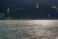 Various kite surfers in action on Lake Resia shot against the light in Curon Venosta, South Tyrol, Italy