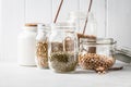 Various legumes: beans, chickpeas, buckwheat, lentils in glass jars on a white background