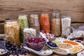 Various legumes: beans, chickpeas, lentils in glass jars on wooden background. Healthy vegetarian food