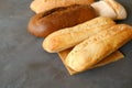 Various loaves of bread. Baked baguette bread and brown loaf of bread on grey table. Royalty Free Stock Photo