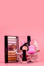 Various make-up products and brushes in shopping cart on pink background. Makeup cosmetics sale concept Royalty Free Stock Photo