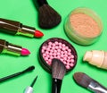 Various makeup products on green background