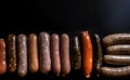 Various meat sausages lie in a row, black background, isolate. AI generated.