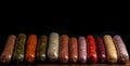 Various meat sausages lie in a row, black background, isolate. AI generated.